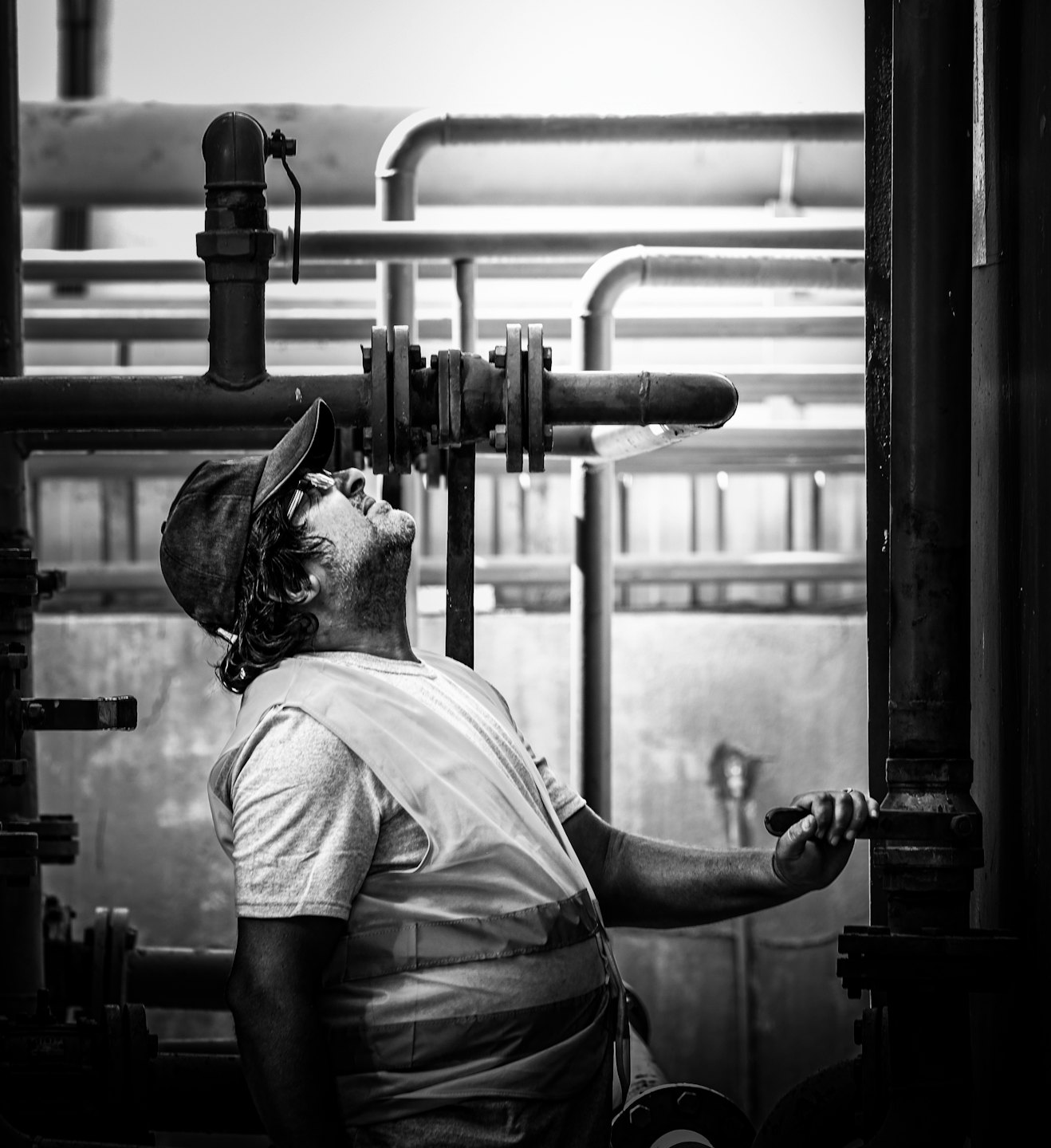 Operaio industriale regola una valvola su un grande impianto di tubazioni.